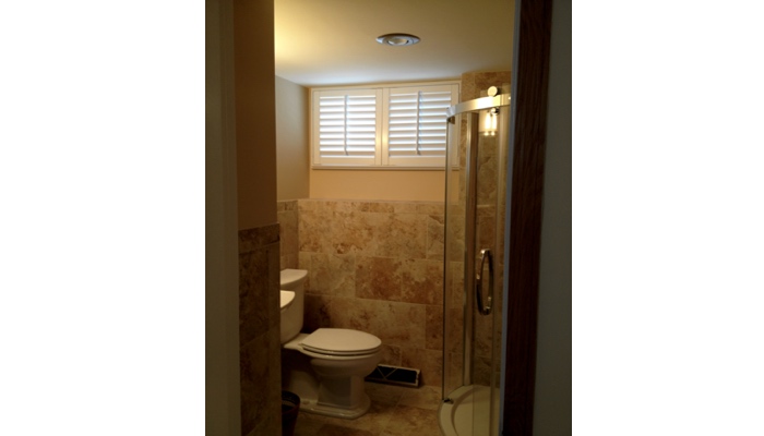 Basement bathroom window covered in white plantation shutters